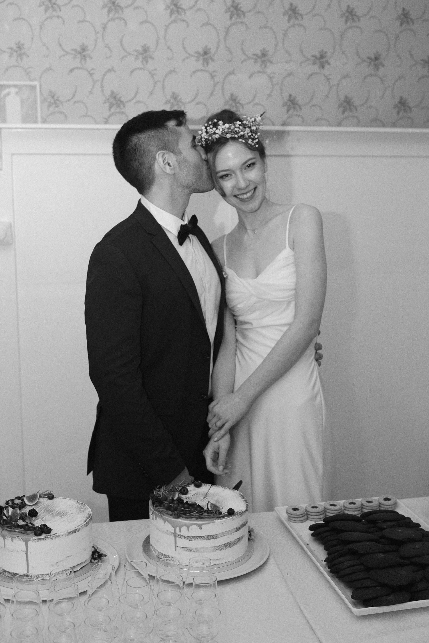 Black and white image of newlyweds sharing intimate moments during cake cutting ceremony.