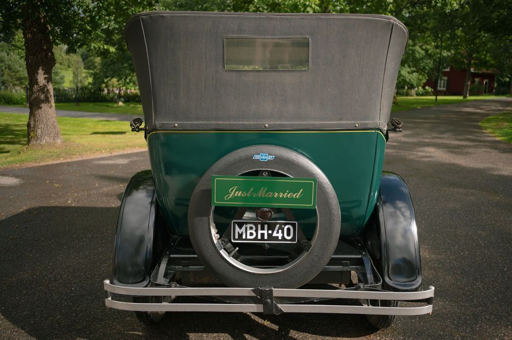 Classic antique car parked outside on gravel driveway.