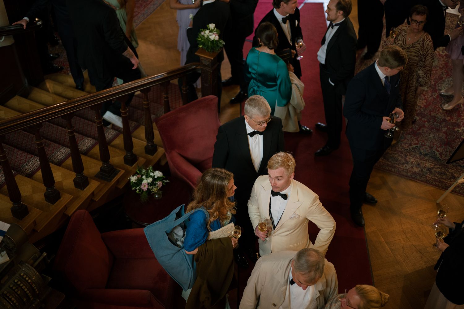 Wedding guests mingle and socialize during an elegant reception in a warmly lit indoor venue.