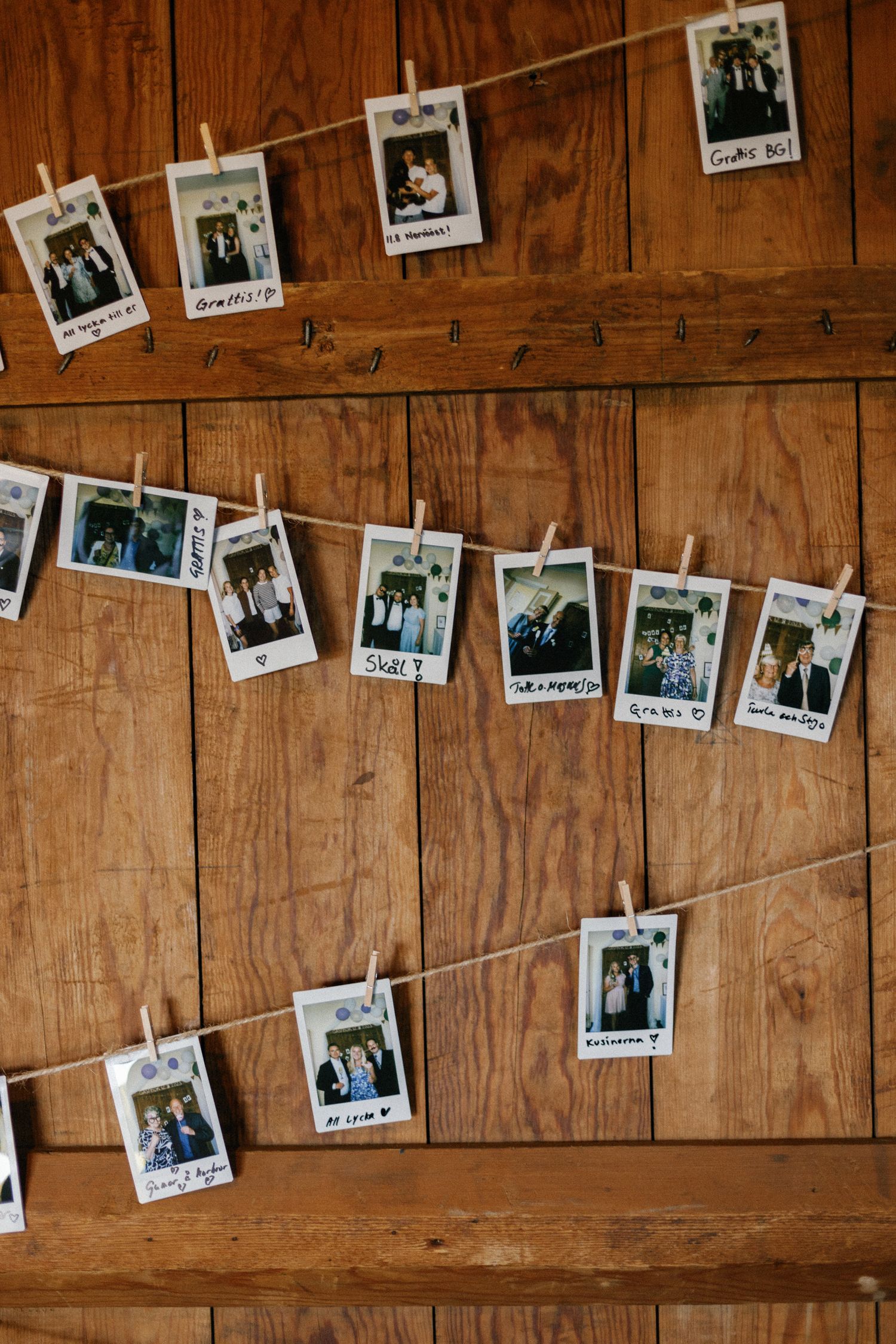 Vintage polaroid photos hung on string against wooden wall as wedding decoration.