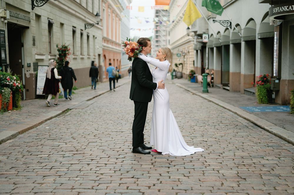 Wedding couple walking along a charming cobblestone street with historic buildings in the background.