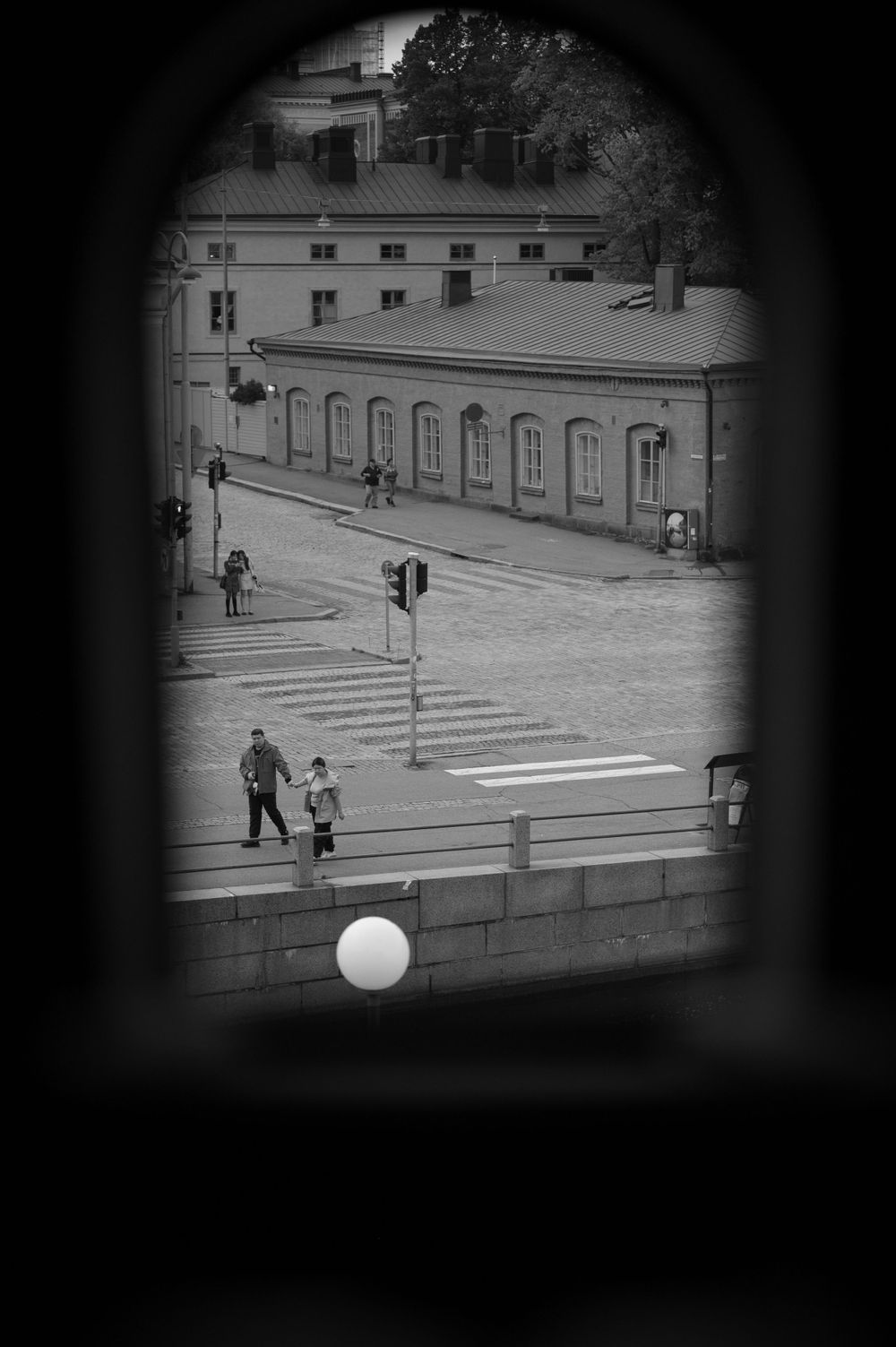 A black and white view through a window showing a crosswalk and building exterior.