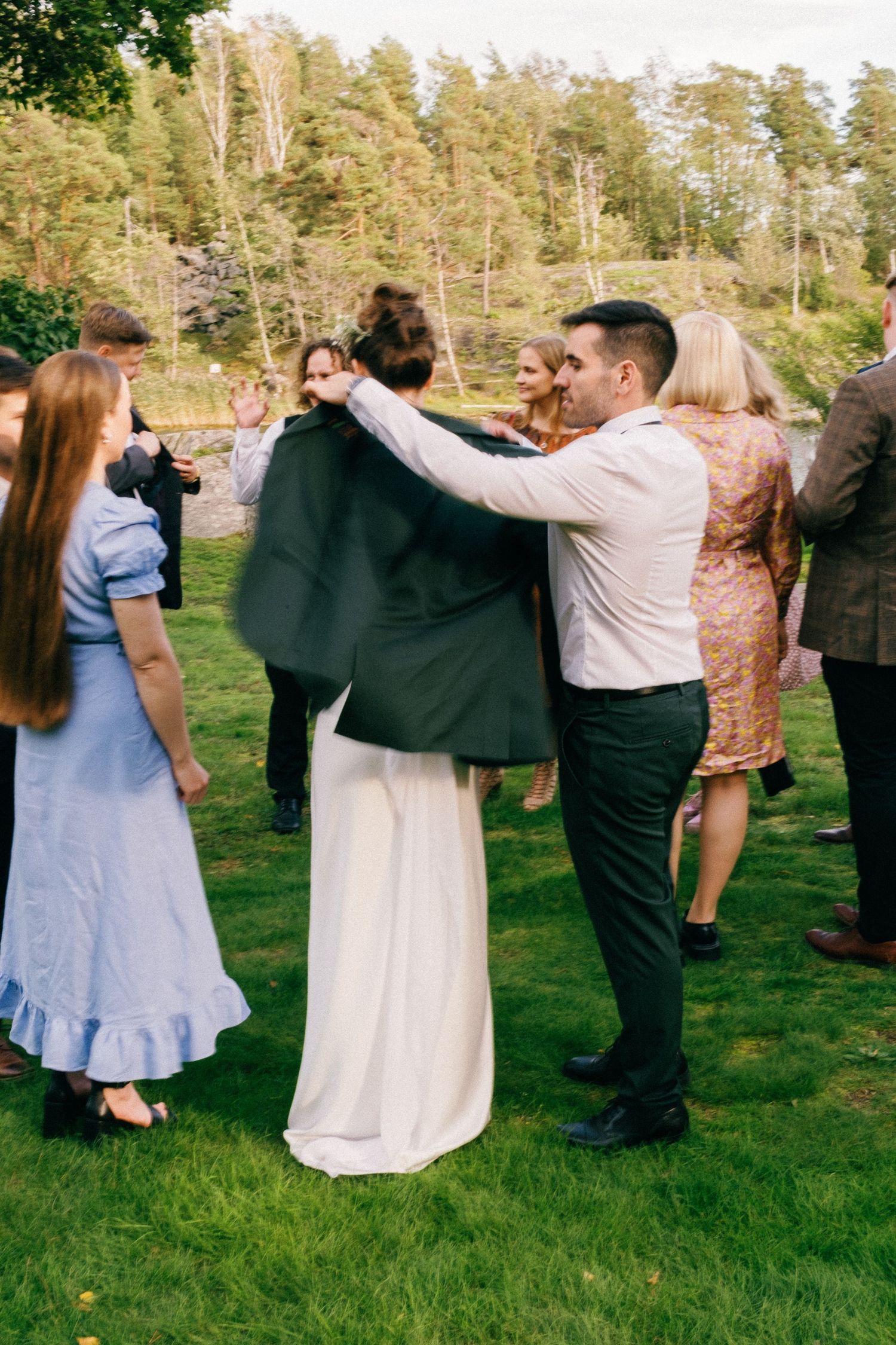 Wedding guests dancing in pairs on a grassy outdoor venue during daytime.