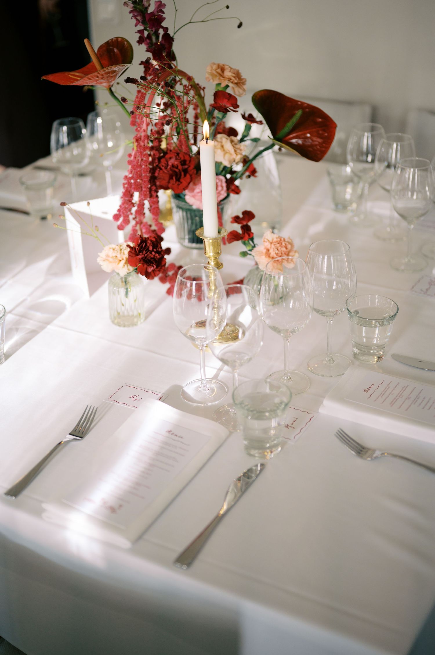 Elegant table settings with white linens, wine glasses, and pink floral centerpieces create a sophisticated dining atmosphere.