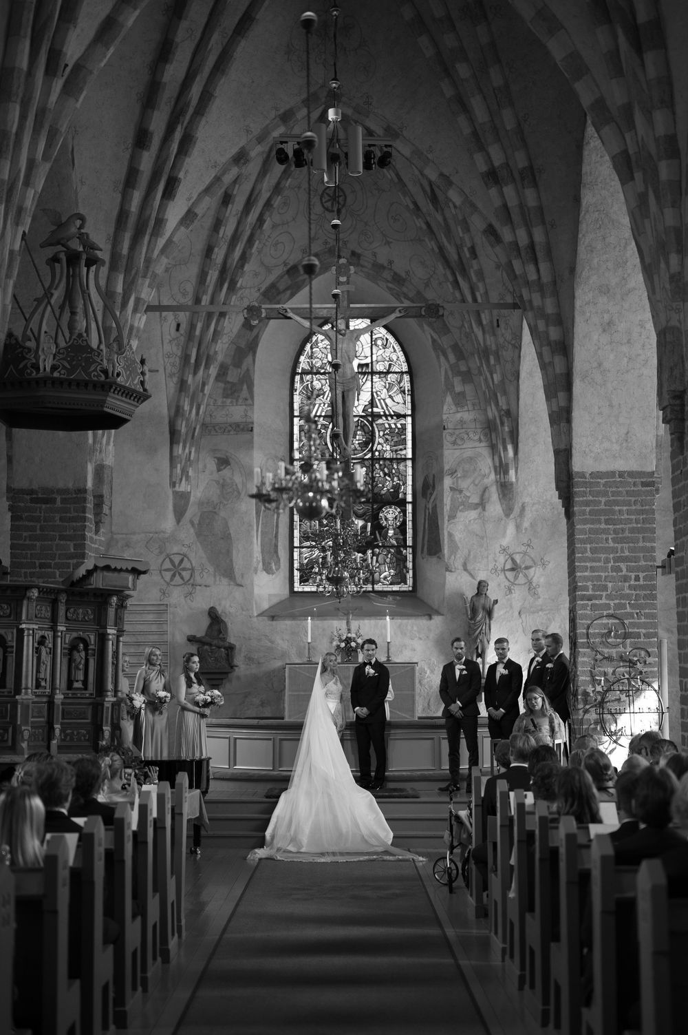 Wedding ceremony in progress at a Gothic church with traditional wooden pews and brick walls.
