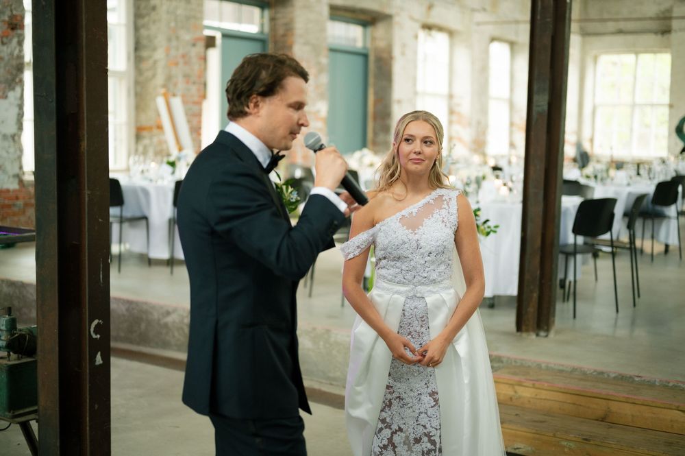 Wedding celebration candid moments captured in an industrial-style venue with exposed brick walls.