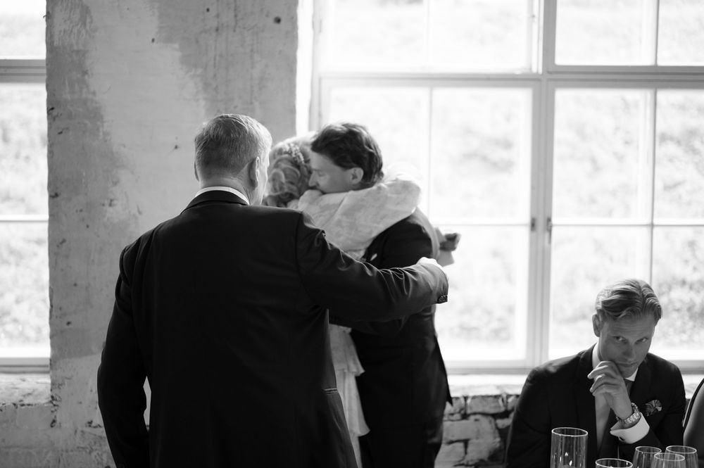 Black and white panoramic view of wedding guests mingling in an industrial space.
