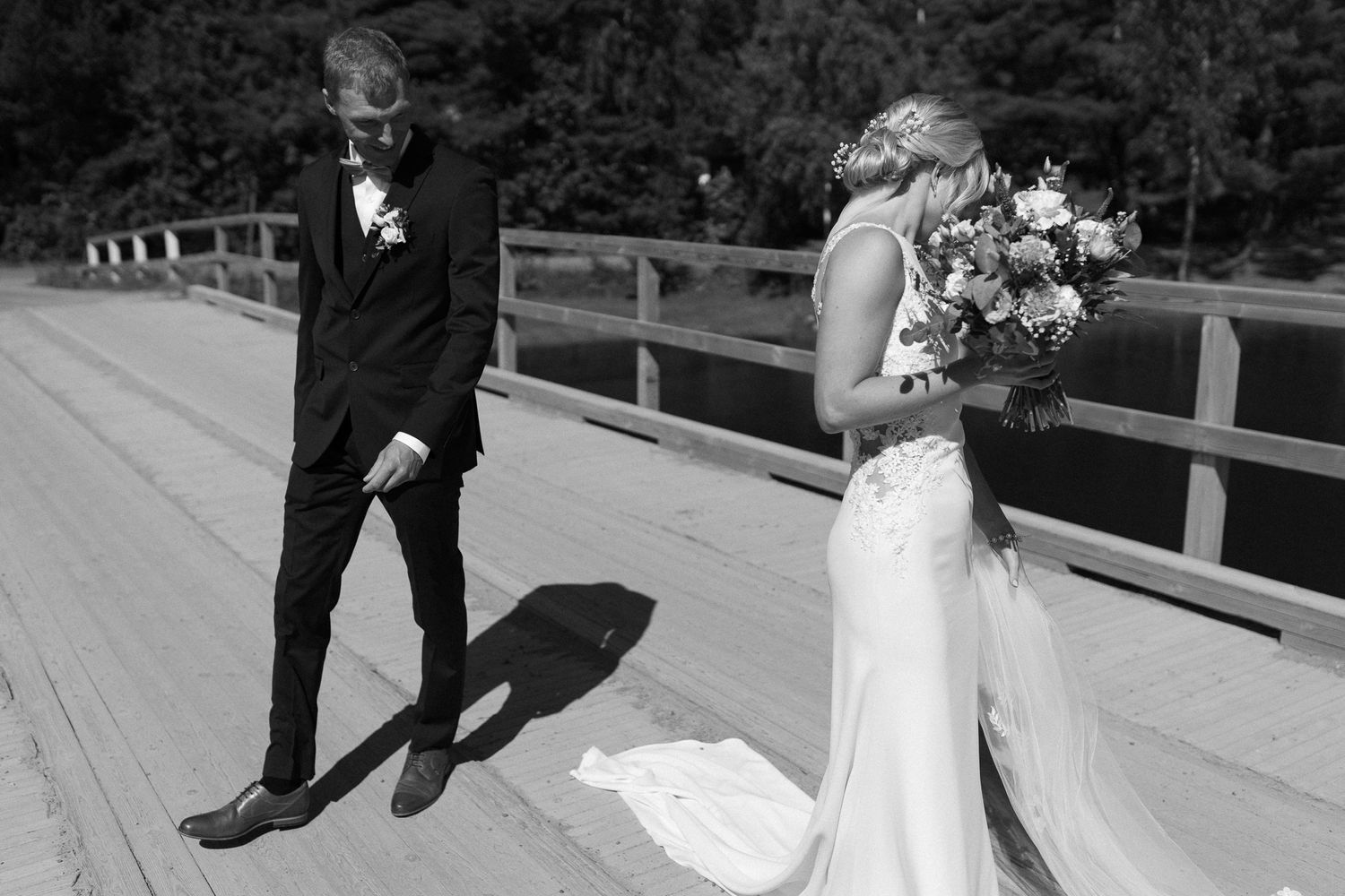 Wedding couple sharing an intimate moment on a wooden deck surrounded by trees.