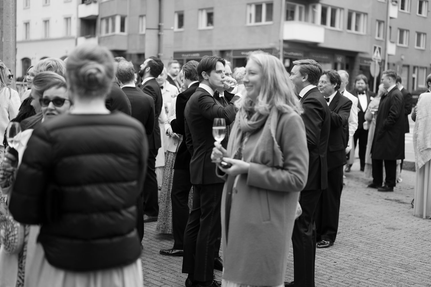 A crowd of people gathered on a city street near apartment buildings during a public event.