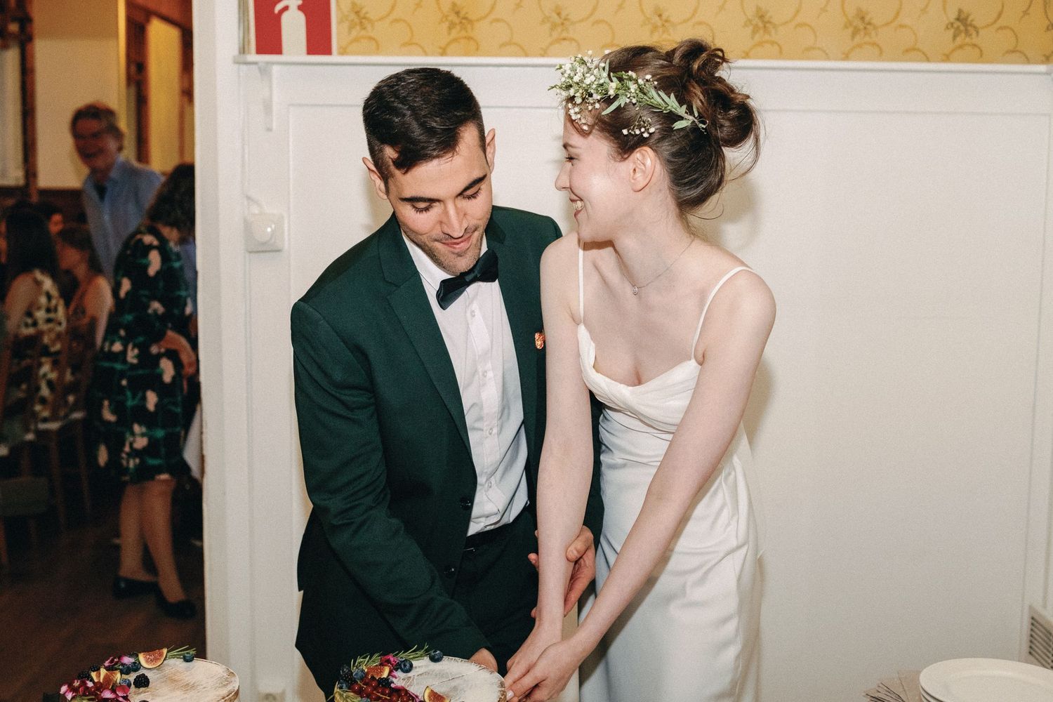 Couple cutting their wedding cake together at an elegant indoor reception.