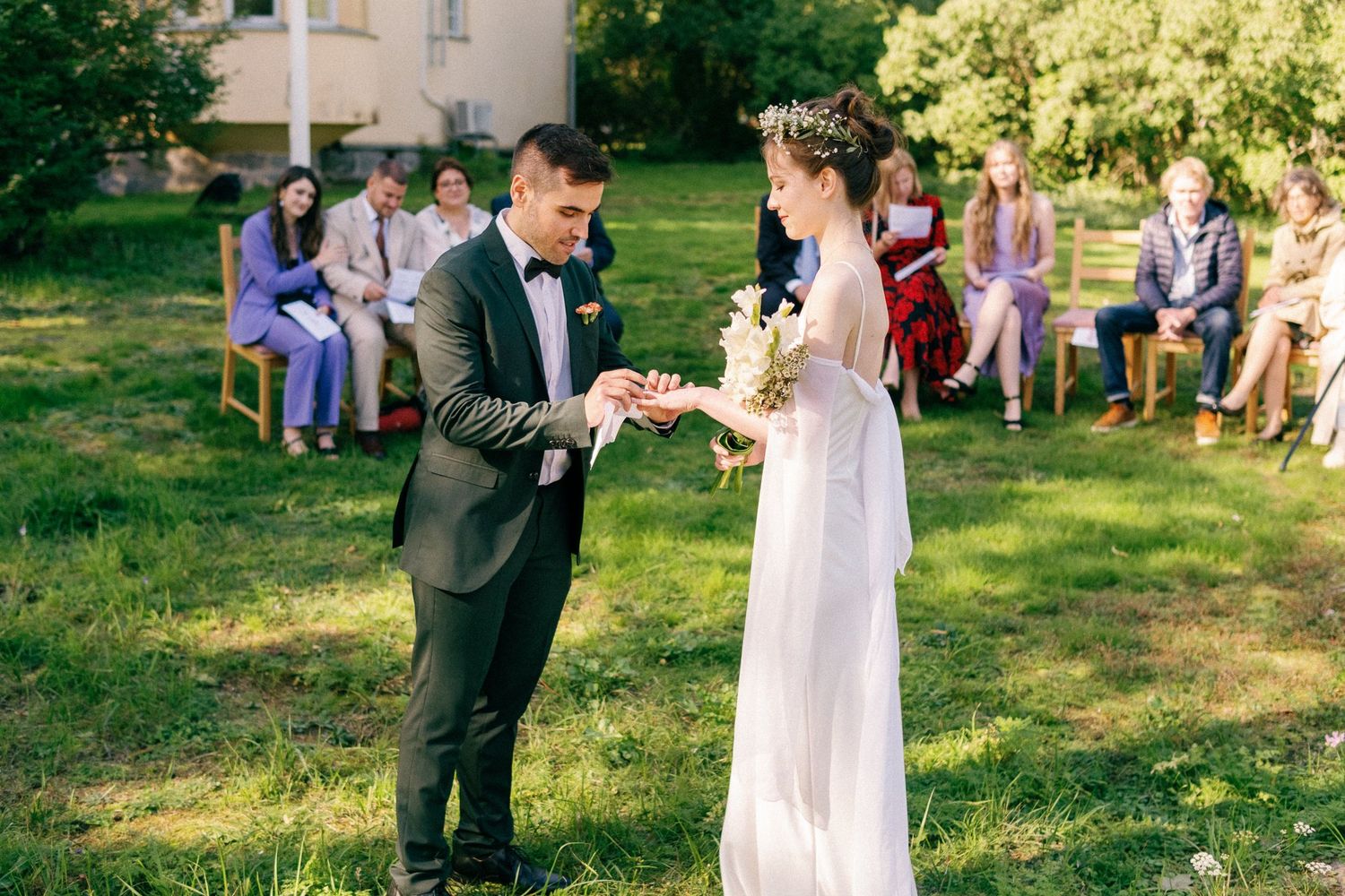 Wedding celebration takes place on manicured grounds with a classic yellow mansion in the background.