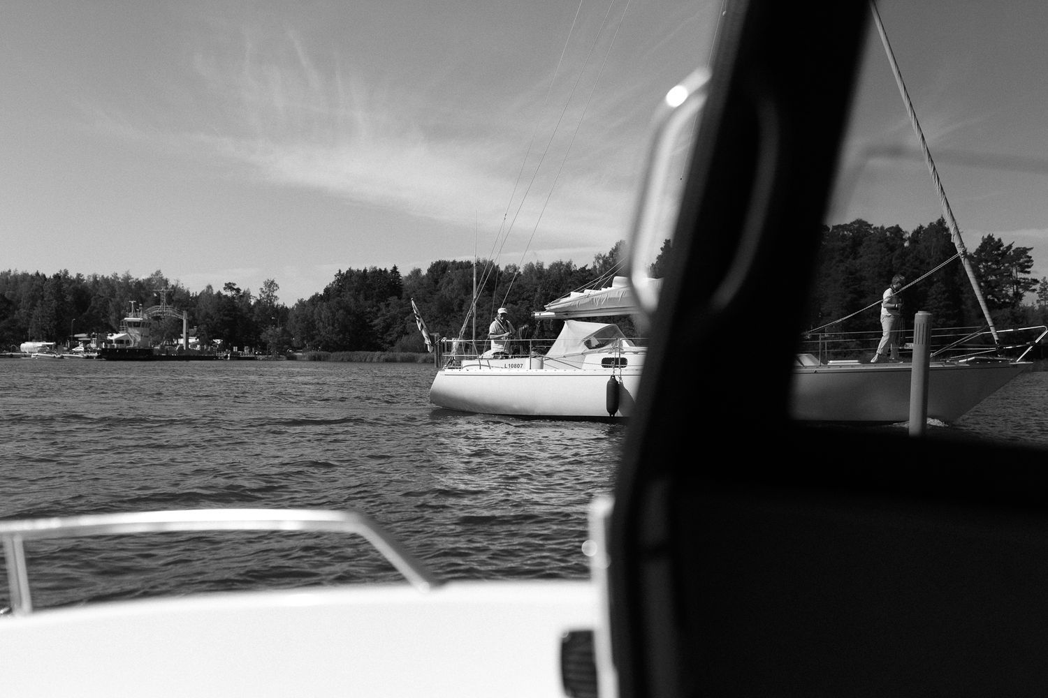Monochrome landscape view of a lake with boats and shoreline.