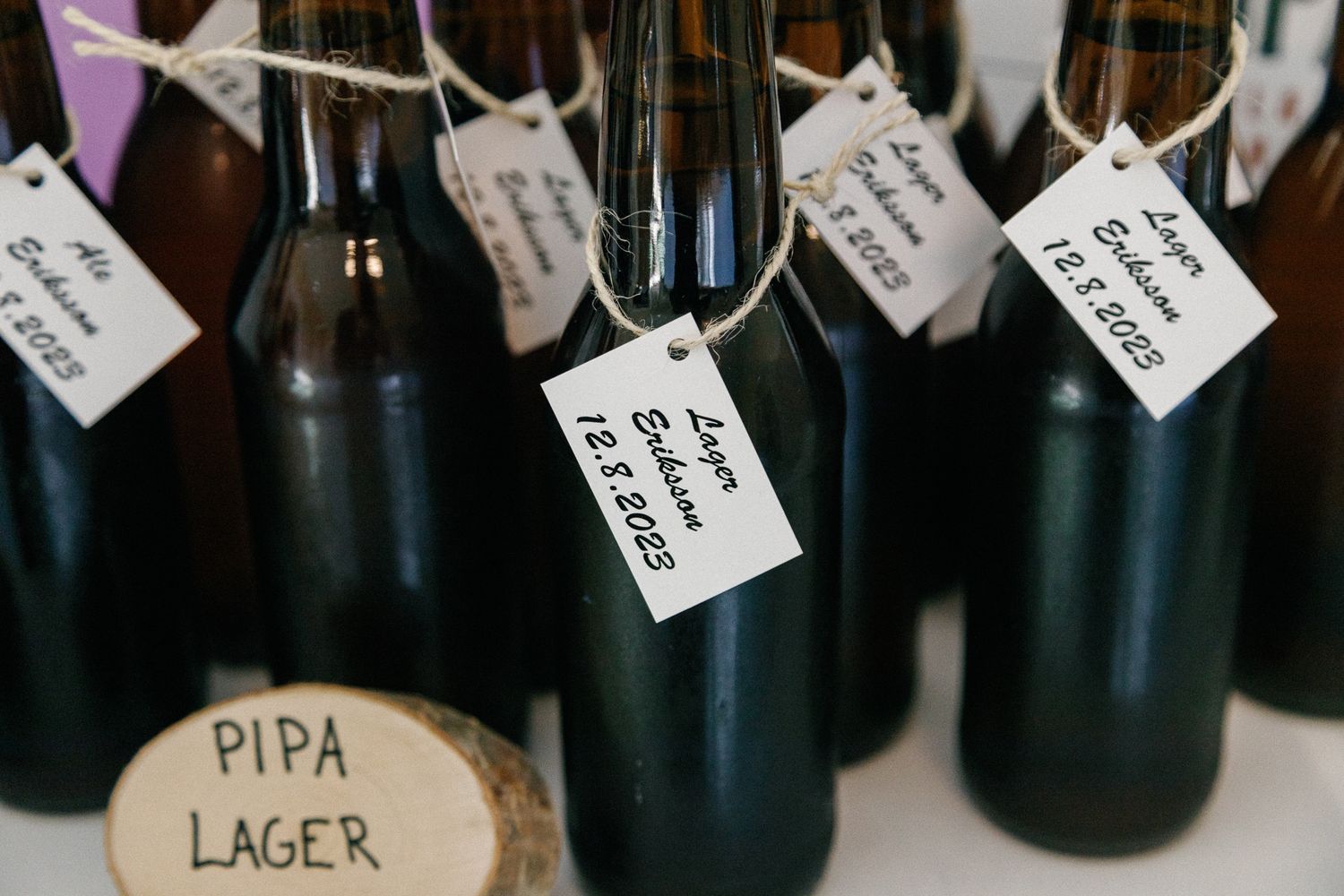 Wine bottles with handwritten labels lined up on a rustic wooden shelf.