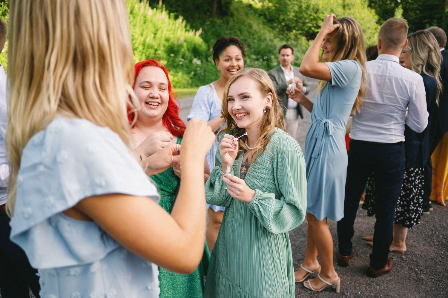 Wedding guests laughing and enjoying drinks during outdoor reception.