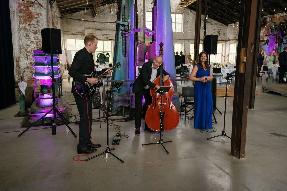 Wedding reception venue with purple uplighting and musicians performing on stage.