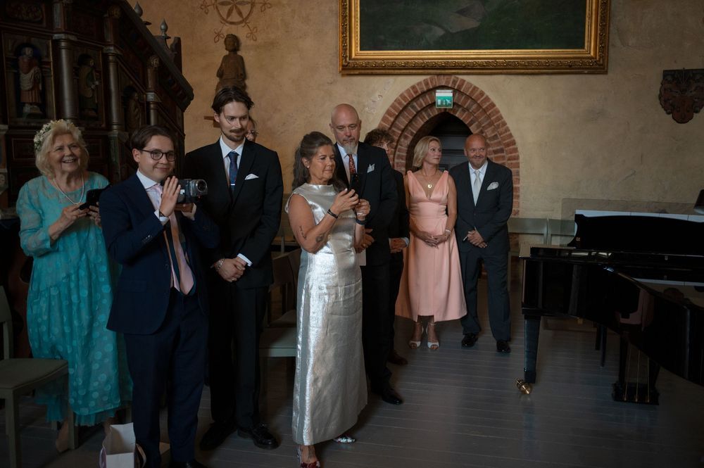 Wedding guests mingling in an elegant church interior with ornate wall decorations.