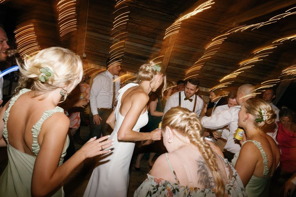 Wedding reception guests dancing and celebrating on a lively dance floor with festive lighting.