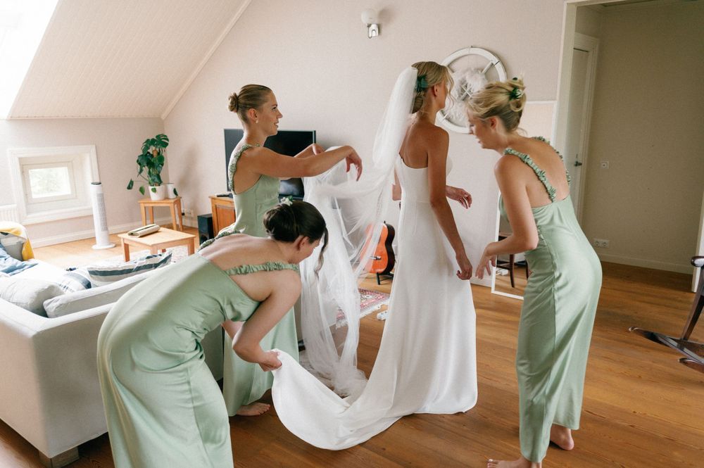 Wedding party in mint green dresses helping with bridal preparations.