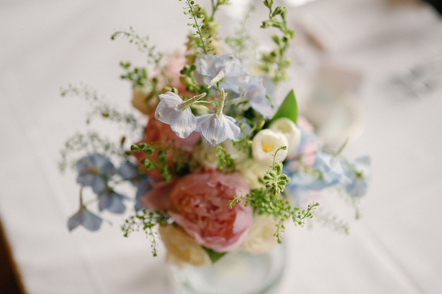 Delicate floral centerpieces with pink and white blooms arranged in small glass vases on an elegant table setting.