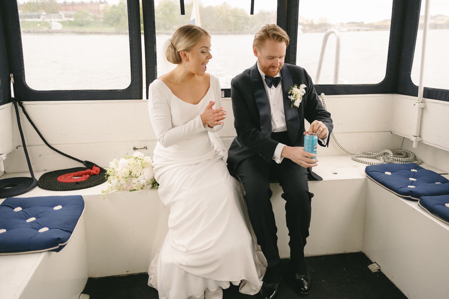 A couple sits together on a white bench in what appears to be a boat or yacht interior.