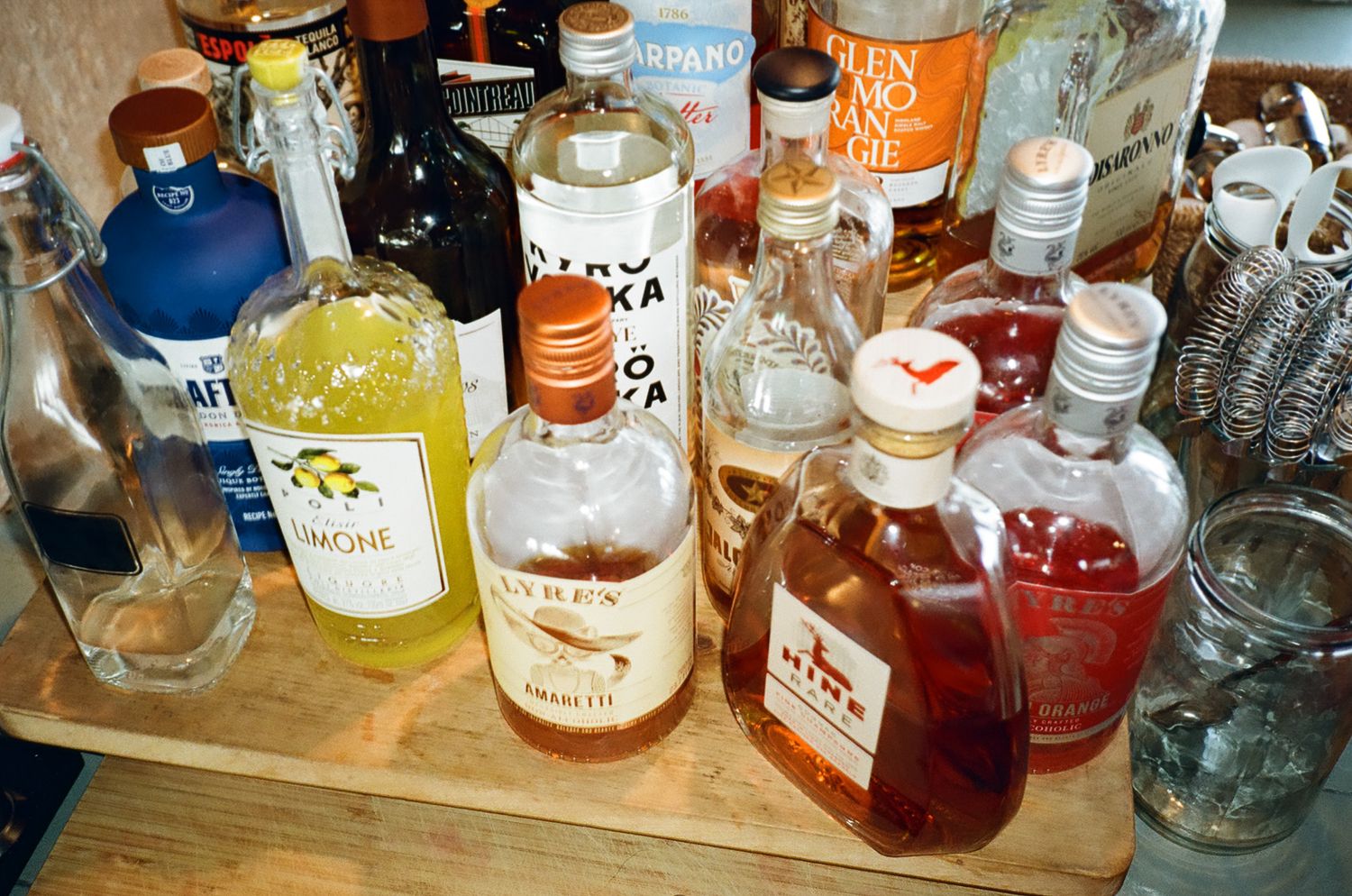 Assorted liquor bottles including limoncello and bourbon displayed on a wooden bar tray.