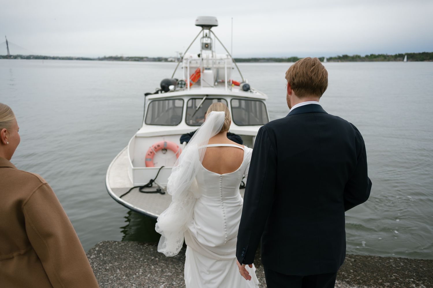 People gather on a boat deck during a nautical celebration or event on a calm body of water.