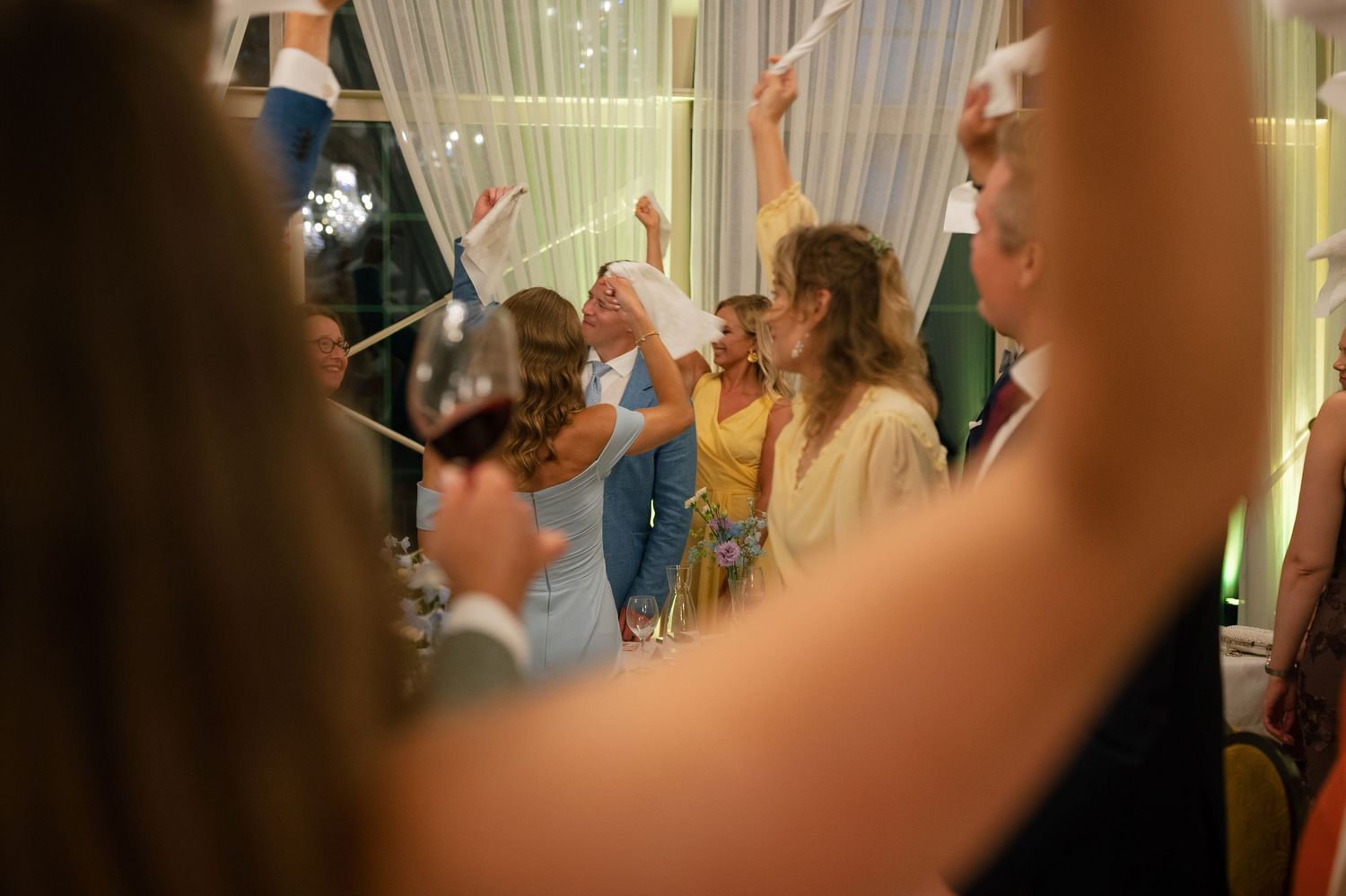 Wedding guests raise their glasses in a celebratory toast at an elegant reception.