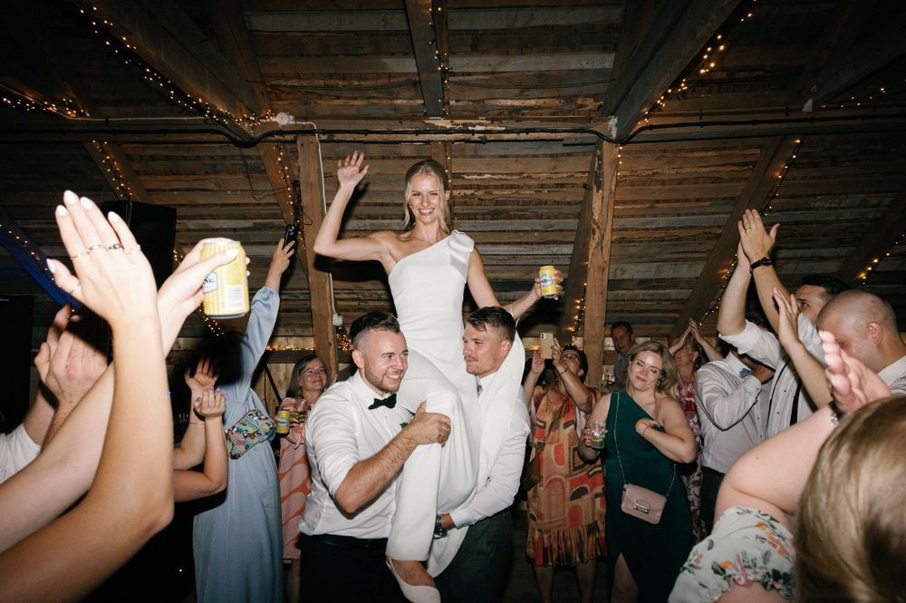 Party guests dance and celebrate in a rustic wooden barn setting.