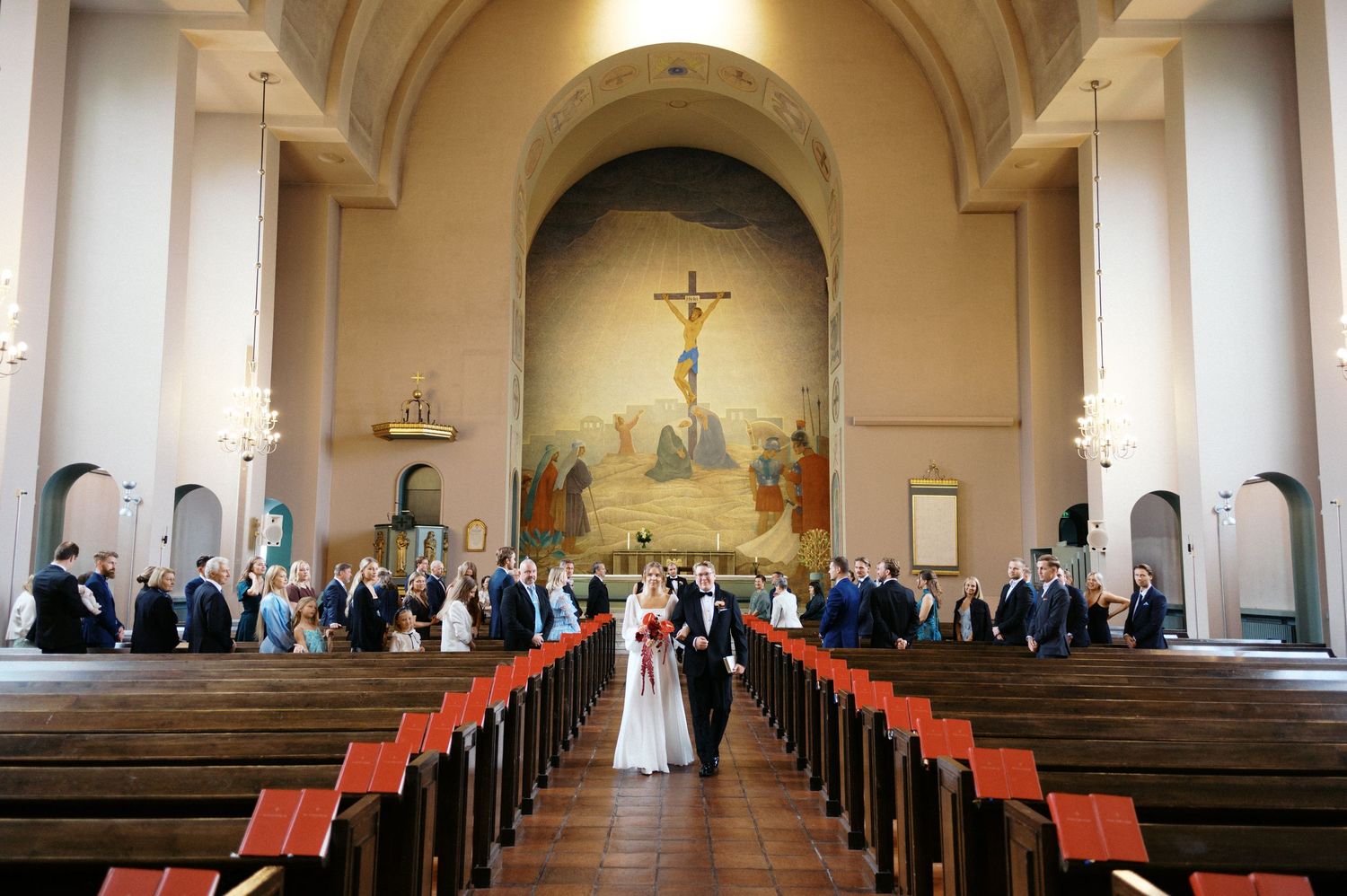 Interior view of a traditional church sanctuary with wooden pews and arched ceiling illuminated by natural light.