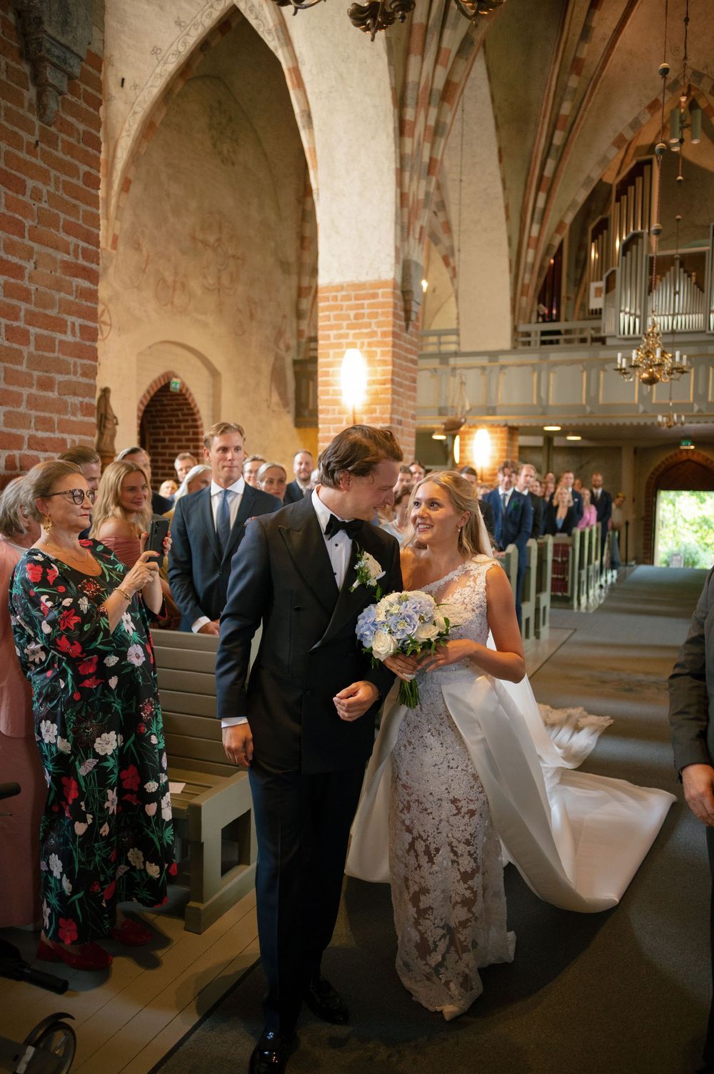 Wedding celebration inside a Gothic-style church with exposed brick walls and elegant chandeliers.