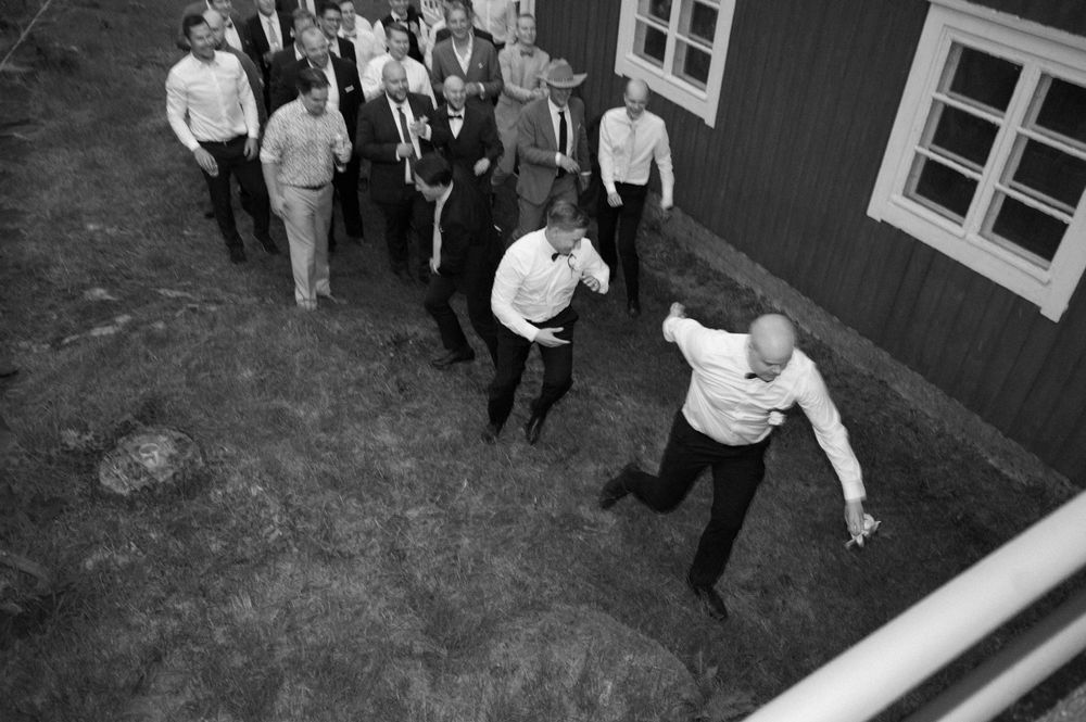 Wedding guests dance and socialize outside a rustic red barn venue.
