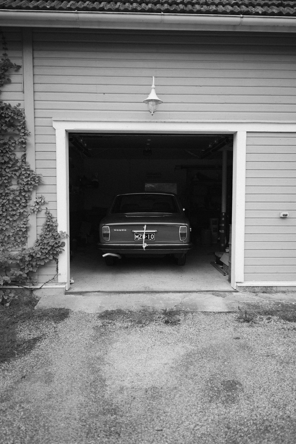 Black and white photo series of vintage car visible through opening garage door.