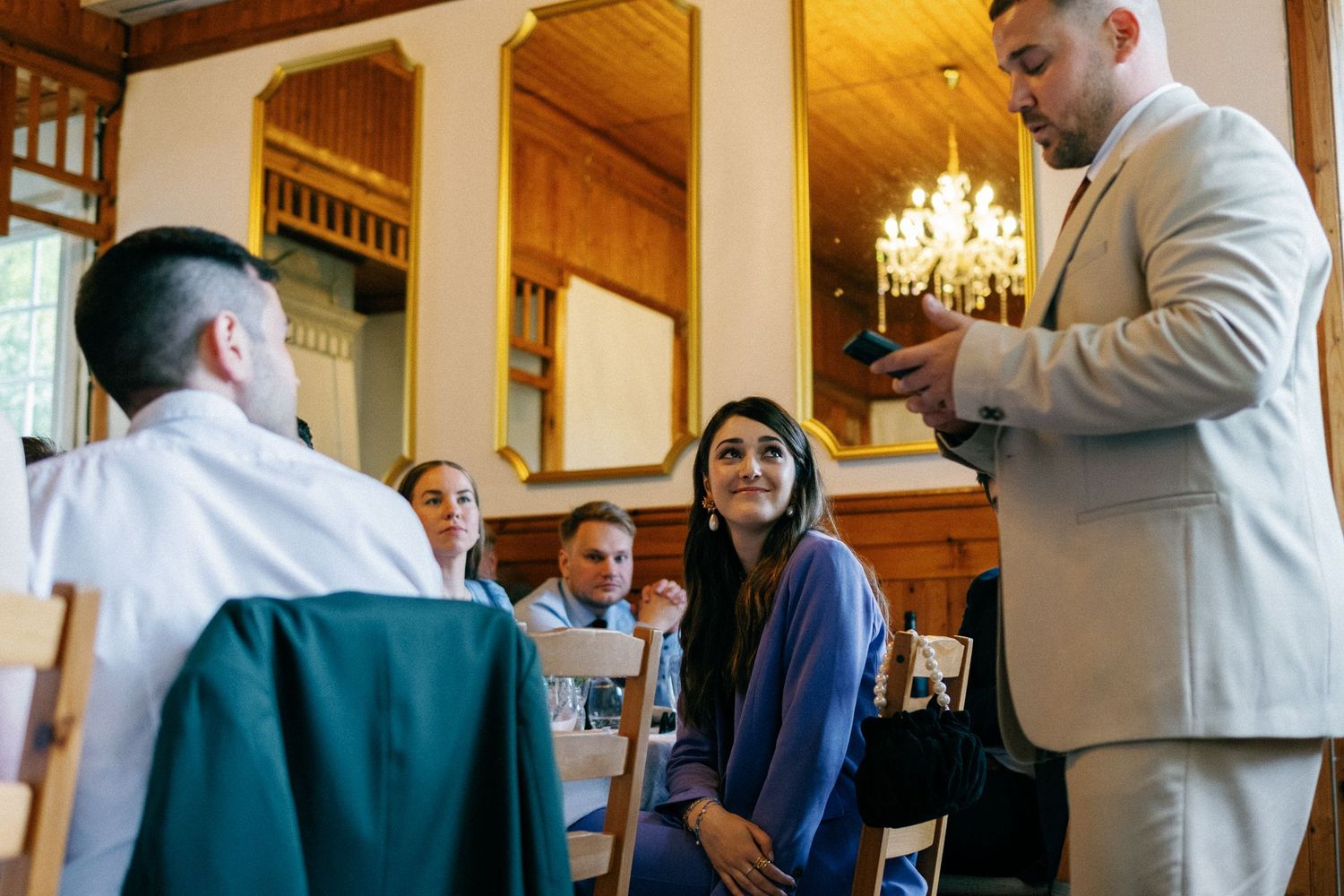 Wedding celebration in a wood-paneled banquet hall with chandelier lighting.