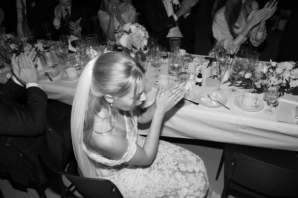 Wedding reception guests seated at long tables with elegant place settings and candlelight.
