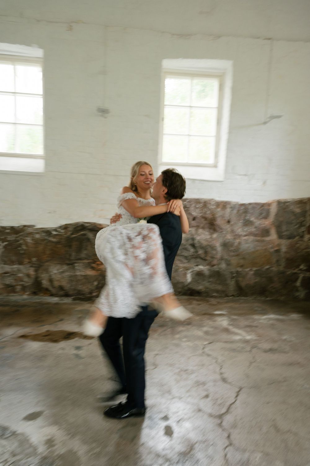 Energetic dance lift performed in a bright industrial space with stone accent walls.