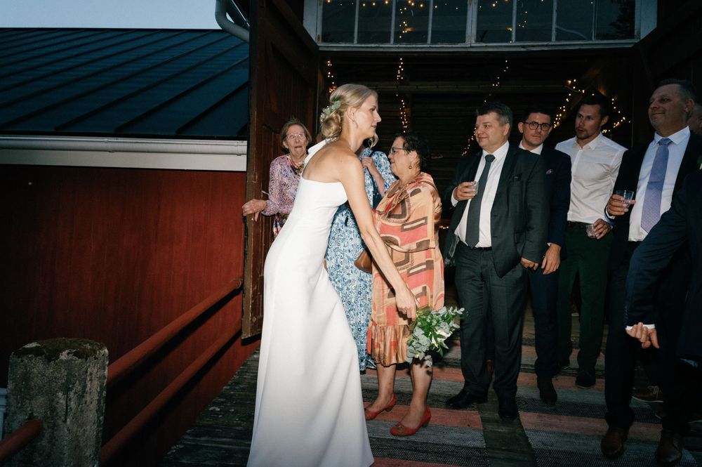 Wedding guests mingle and dance at an outdoor venue near a building.