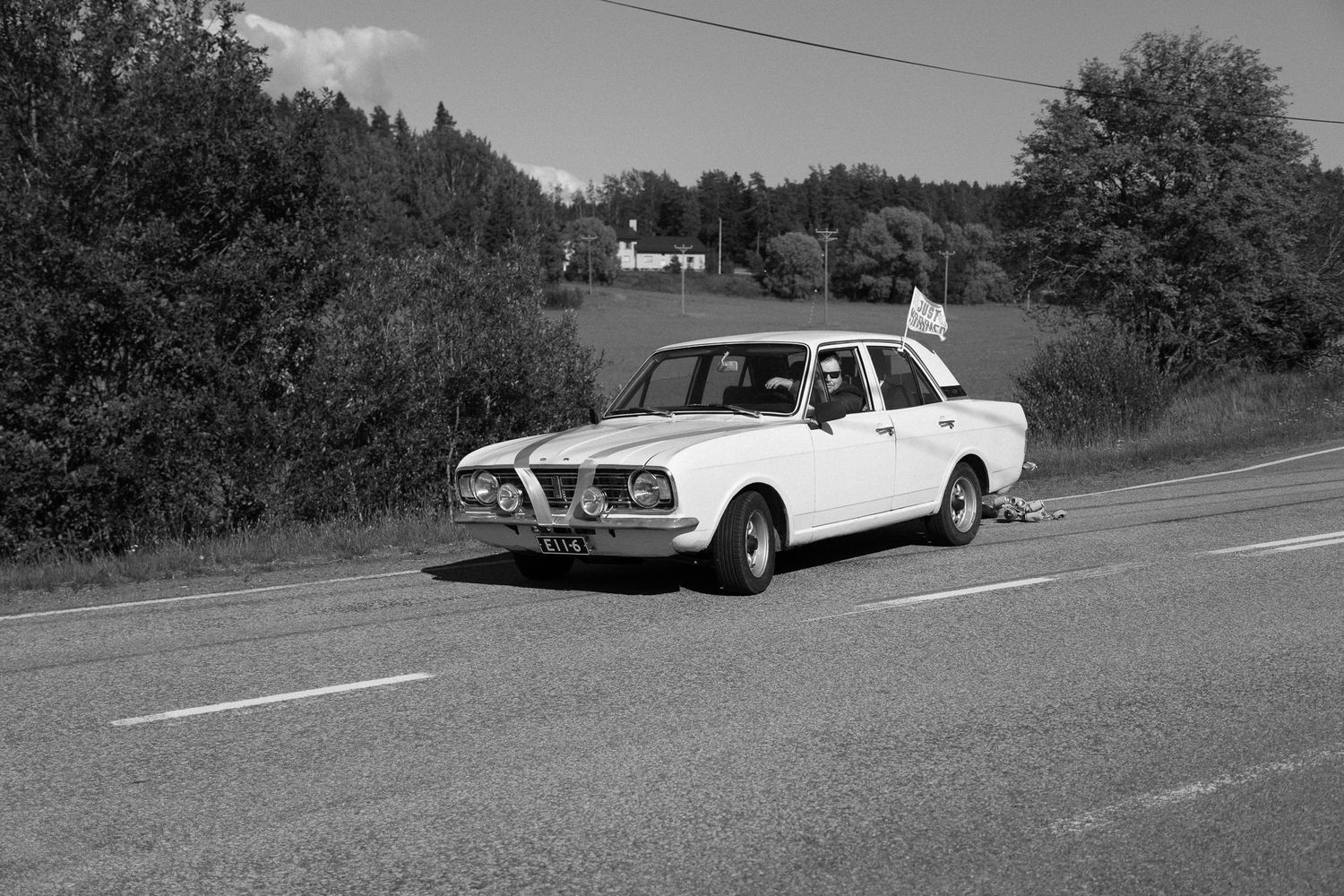 Classic vintage cars parked along rural road in black and white photography.