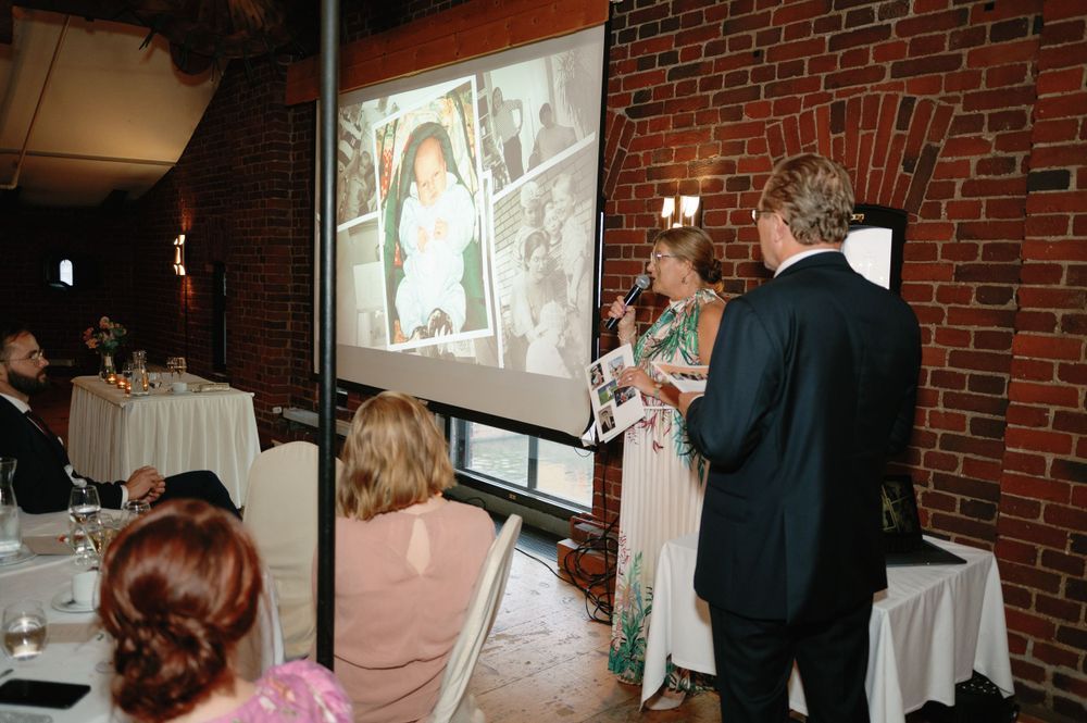 A slideshow presentation being shown on a projector screen in a brick-walled venue.
