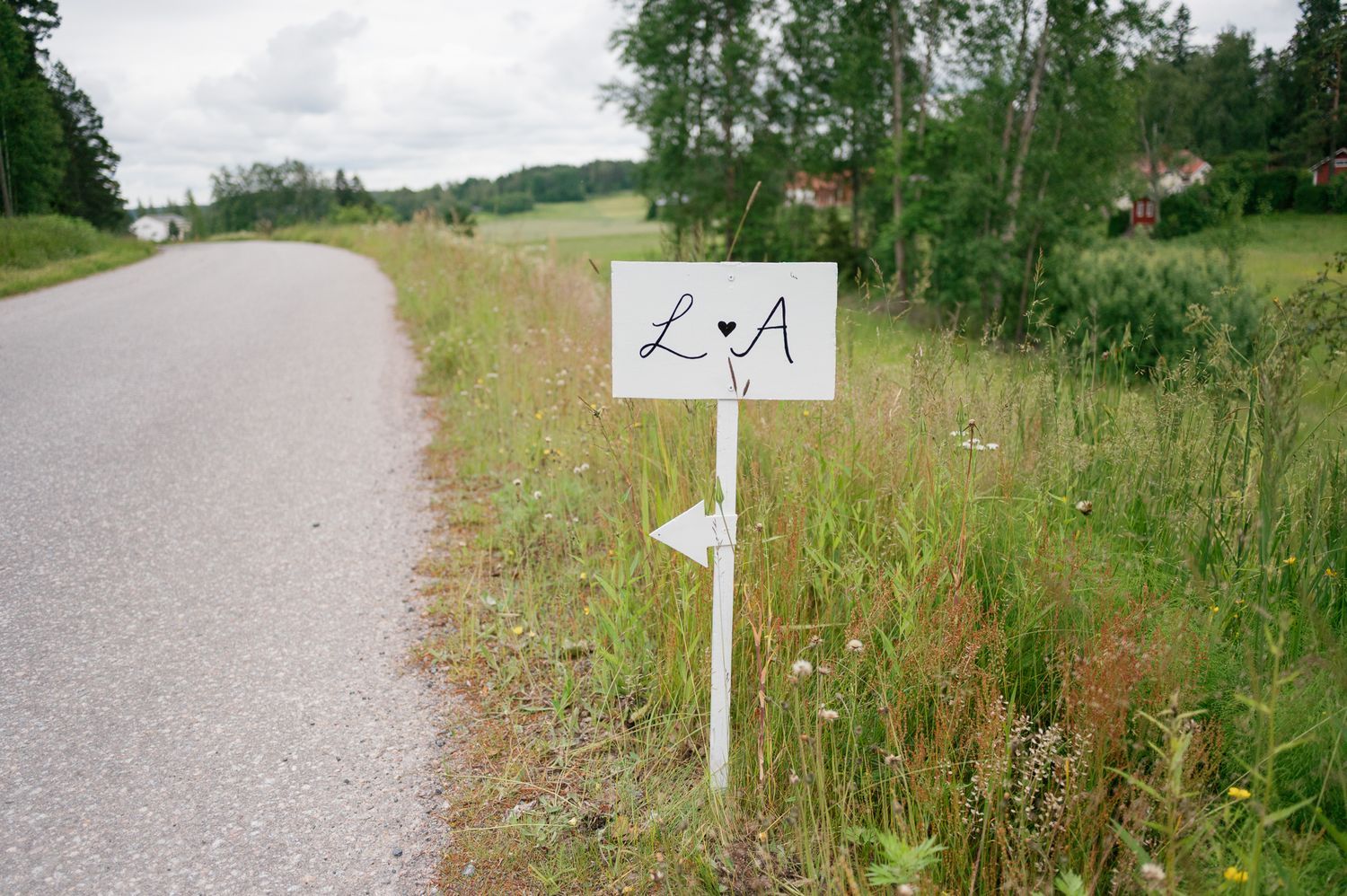 Scenic dirt path through green countryside with directional signs marking a trail route.