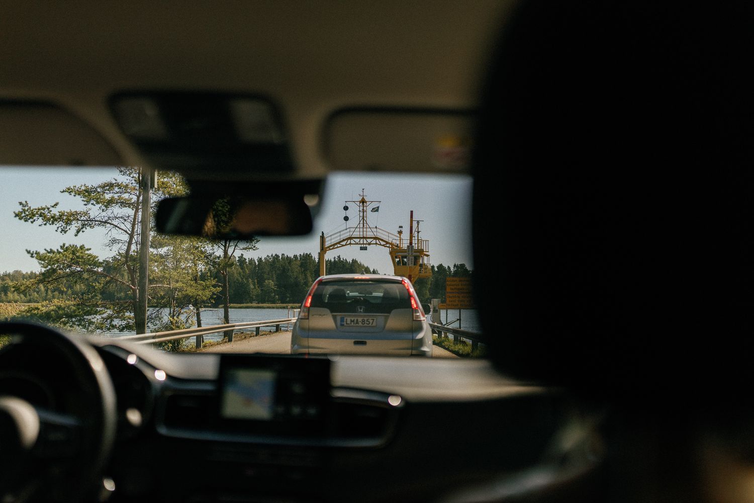 View through car windshield showing sunny outdoor scenery.