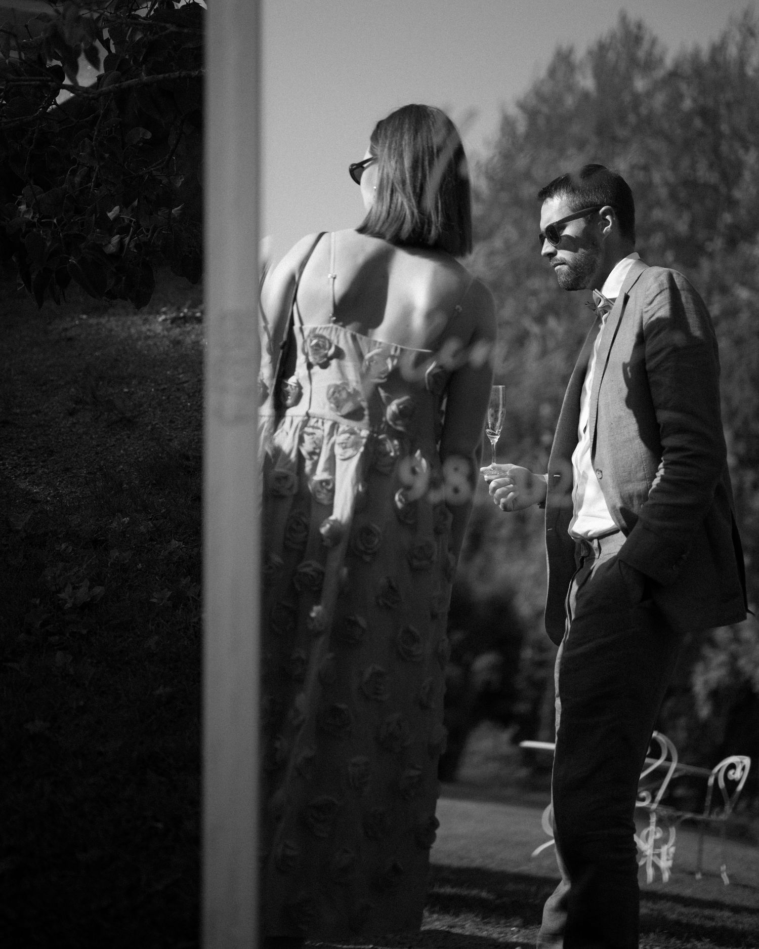 Black and white artistic photo of guests conversing at an outdoor summer event.
