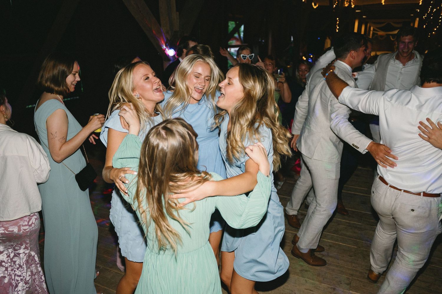 Lively dance floor filled with guests celebrating at wedding reception.