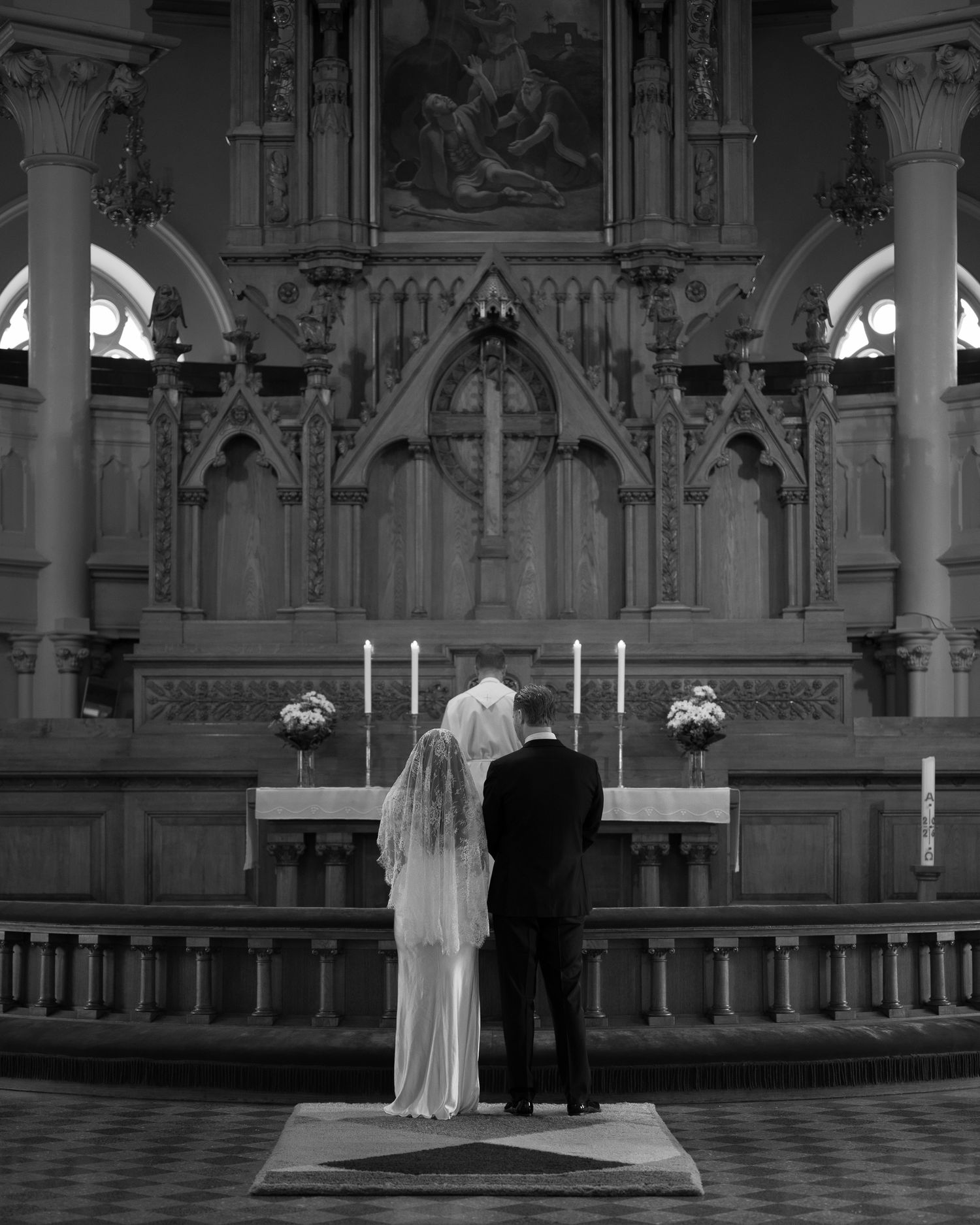 Black and white photo of a bride and groom standing at a church altar during their wedding ceremony.