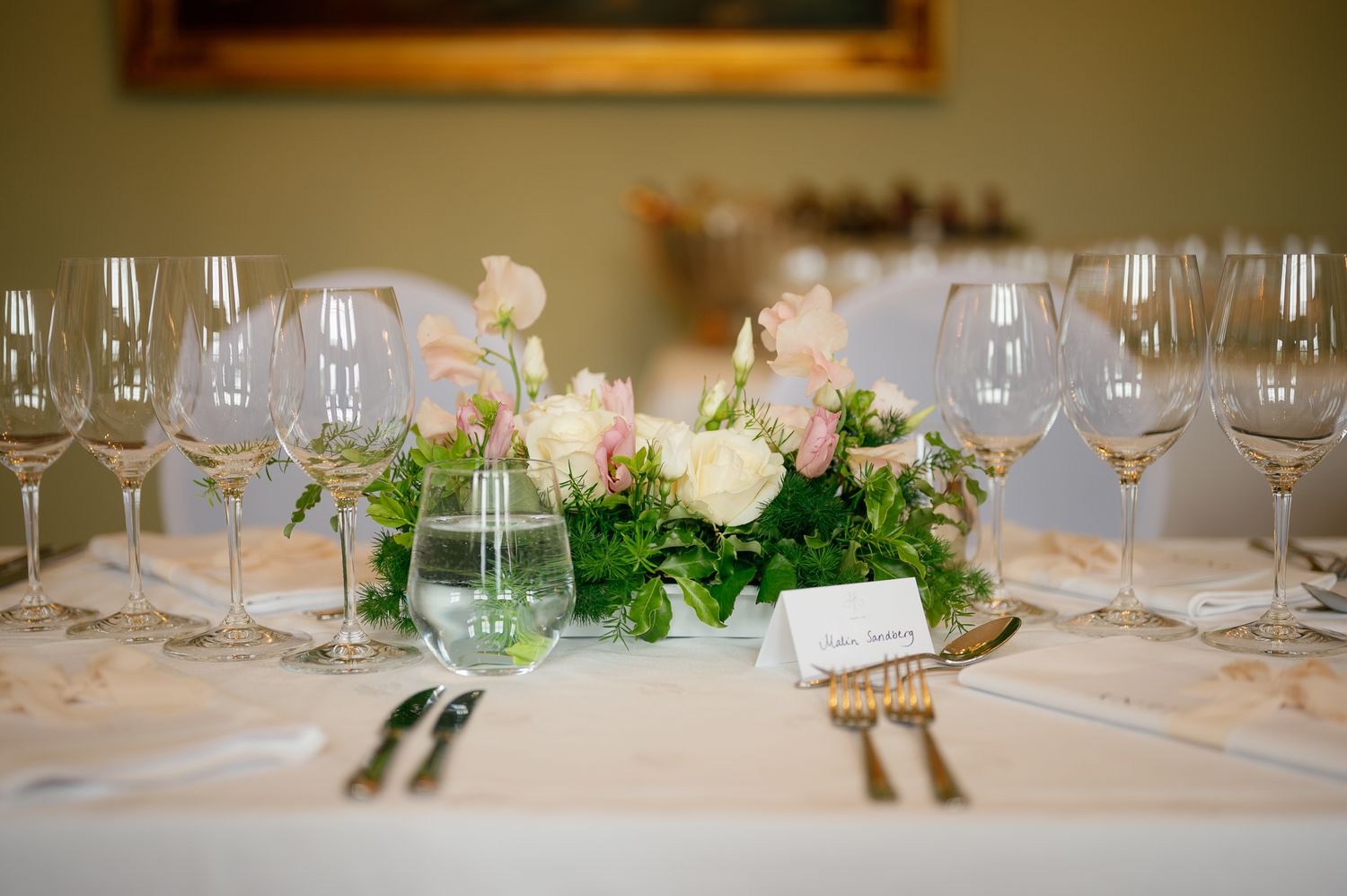 Row of empty wine glasses and formal place settings arranged on white tablecloth for upscale dining.