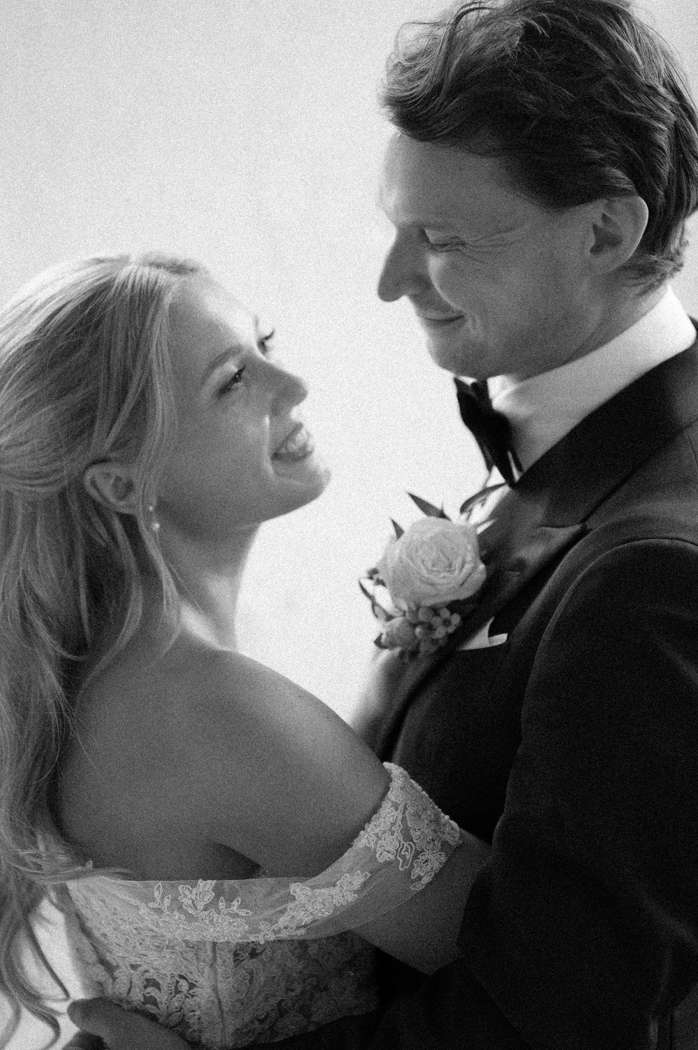 A black and white wedding portrait showing the couple sharing an intimate moment with genuine smiles.