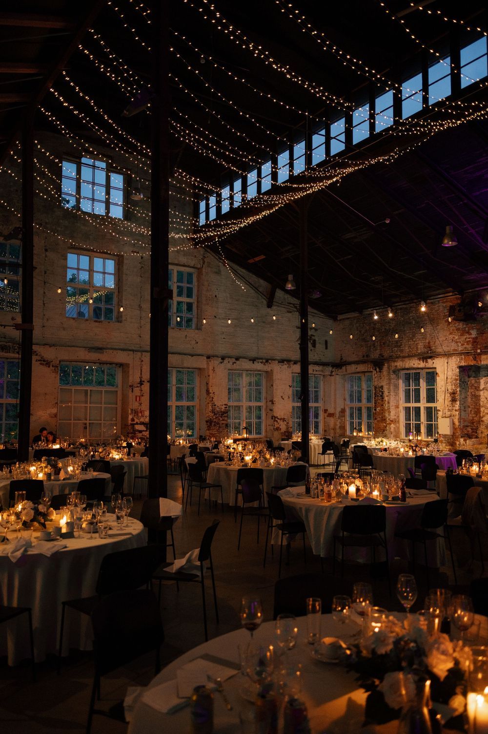 Wedding reception hall decorated with romantic string lights and candlelit tables creating a warm ambiance.