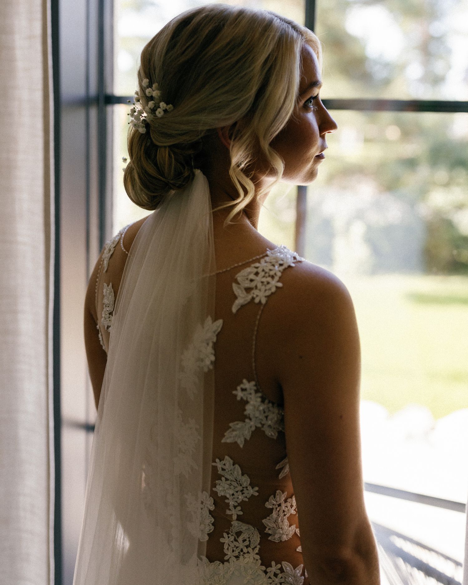Sunlit bridal portrait showing intricate lace details of a wedding veil.