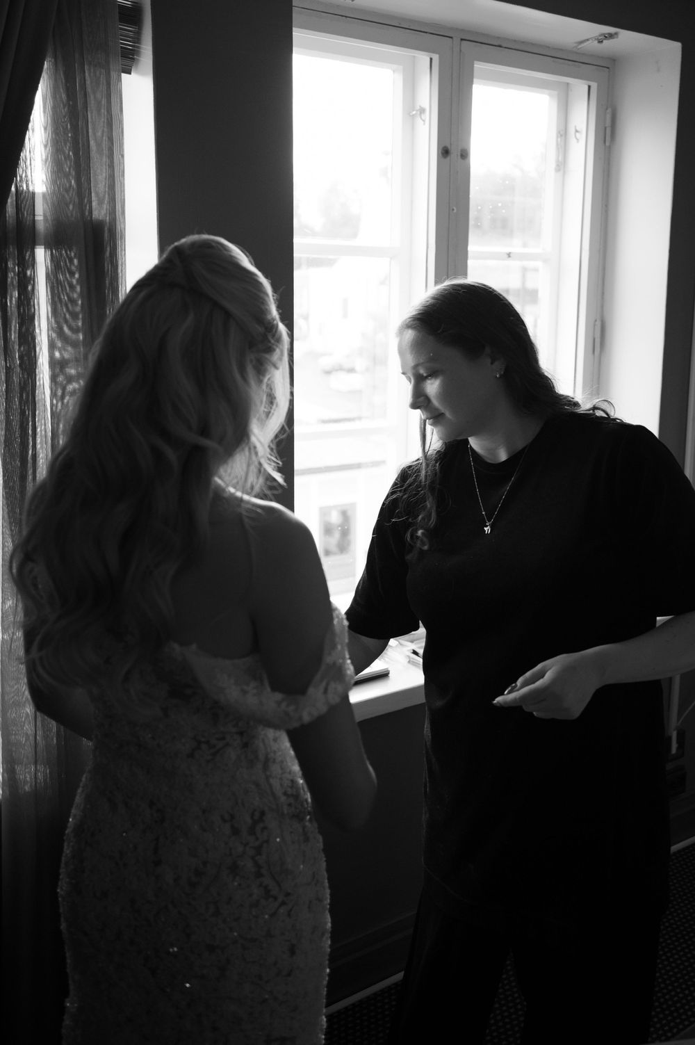 Figures in silhouette stand near a bright window with natural light streaming in.