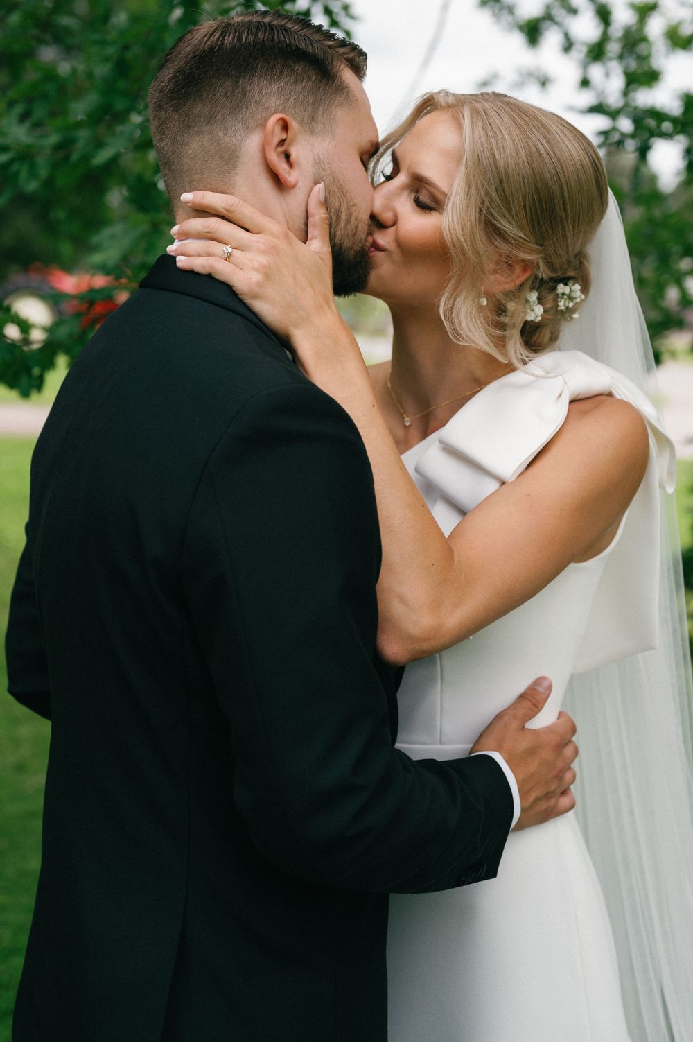 A romantic wedding embrace captured in an outdoor garden setting.