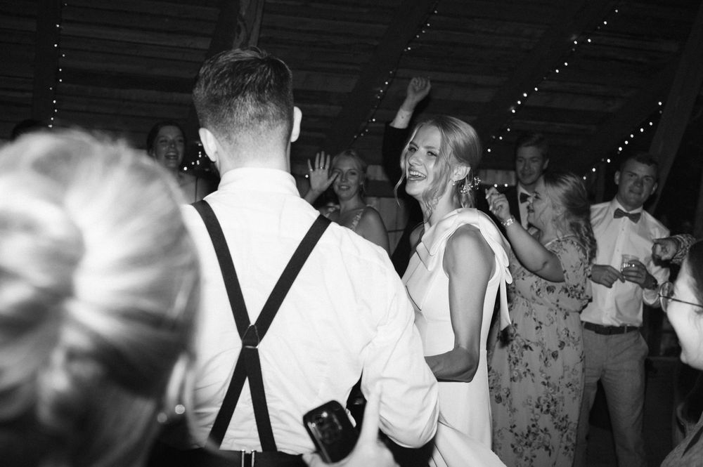 Guests dancing and celebrating at a dimly lit indoor wedding reception.